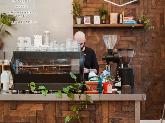 Ein Mann hinter einem großen Kaffeevollautomaten im Café