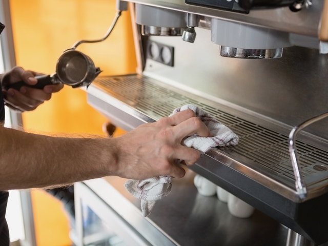 Eine Person reinigt einen Kaffeevollautomaten