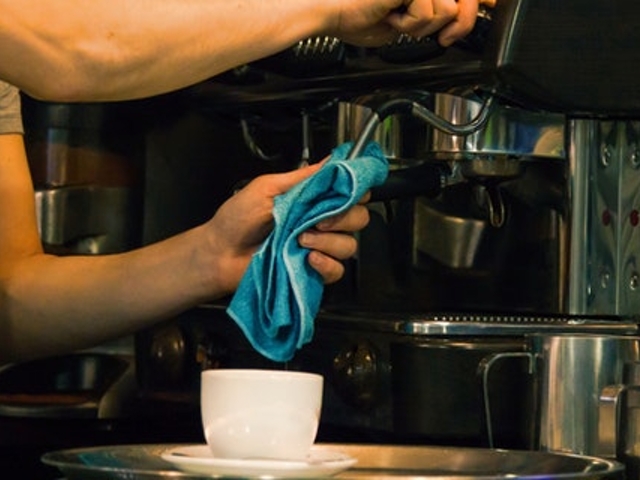 Eine Person säubert einen Kaffeevollautomaten