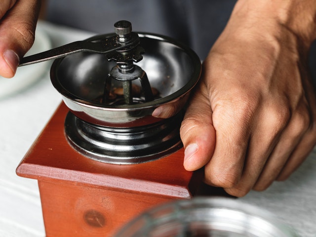 Kaffee wird vom Barista in einer Kaffeemühle gemahlen