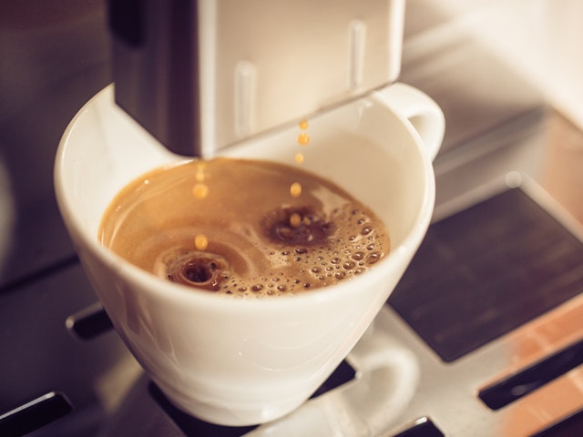 Aromatischer Kaffee der vom Kaffeevollautomaten in die Tasse träufelt