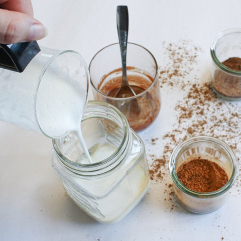 Milchschaum Aufgeschäumte Milch, die in ein Glas gegossen wird