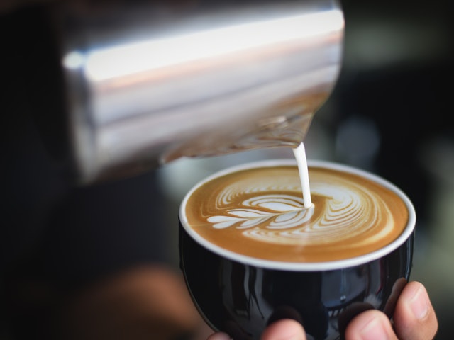 Milchschaum wird in die Kaffeetasse gegossen