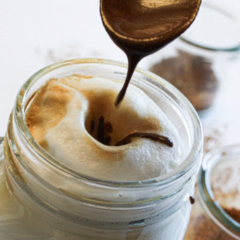Gewürzsirup Der Gewürzsirup tropft von einem Löffel in den Caffe Latte