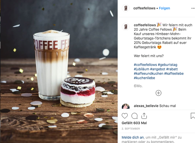 Ein Screenshot der Coffee Fellows auf Instagram. Zum Jubiläum weht Konfetti durch das Bild. Auf einem Holztisch stehen ein Latte Macchiato und ein pink-weiß-braunes Jubiläumstörtchen.