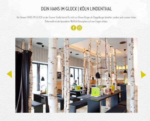 Ein Screenshot der Hans im Glück-Website, die den Standort Köln Lindenthal zeigt. In dem Restaurant ragen Birkenstämme aus dem Boden und das Design gleicht einem Märchenwald. Überall sind grüne Farbakzente auf den Tischen verstreut.