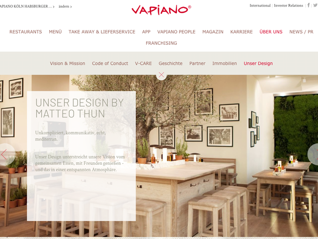 Ein Screenshot der Vapiano-Website vom Standort Köln Rudolfplatz. Dort präsentieren sie ihr Design von Experte Matteo Thun. Das Restaurant strahlt ein gemütliches Ambiente aus. Helle Holzmöbel und italienische Kräter schmücken den Raum und inmitten eines Tisches wäscht ein hundertjähriger Olivenbaum. An den Wänden hängen traditionelle italienische Bilder.